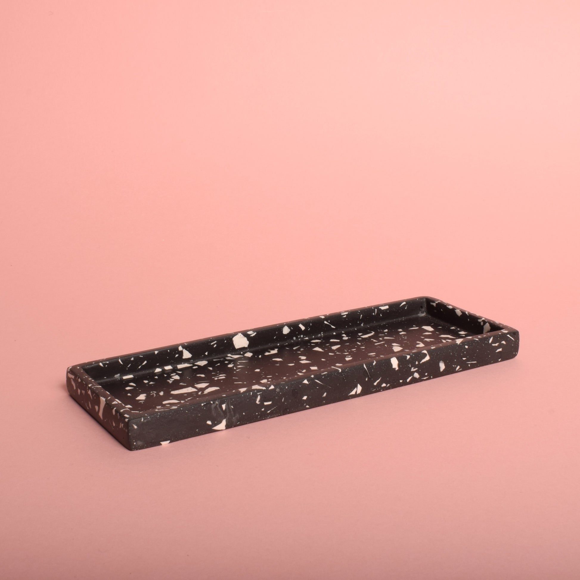 A black rectangular trinket tray with white terrazzo chips