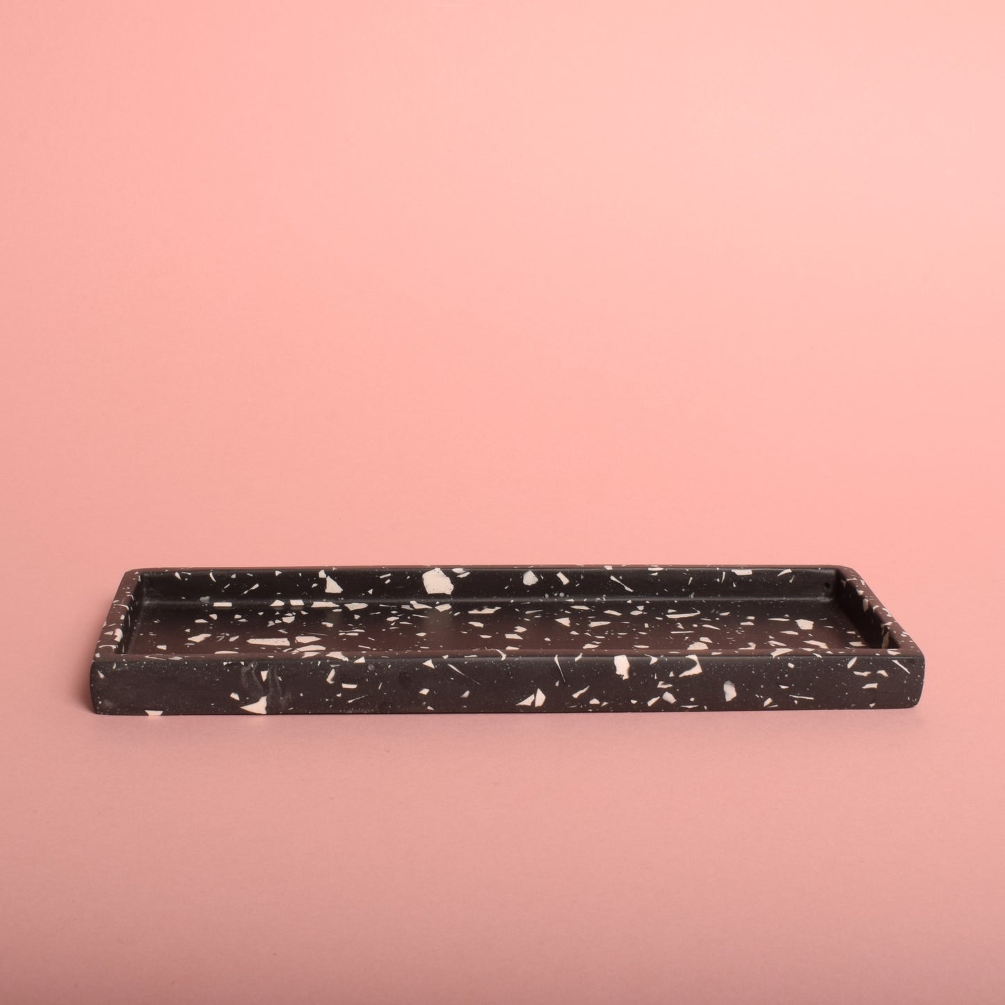 A black rectangular trinket tray with white terrazzo chips