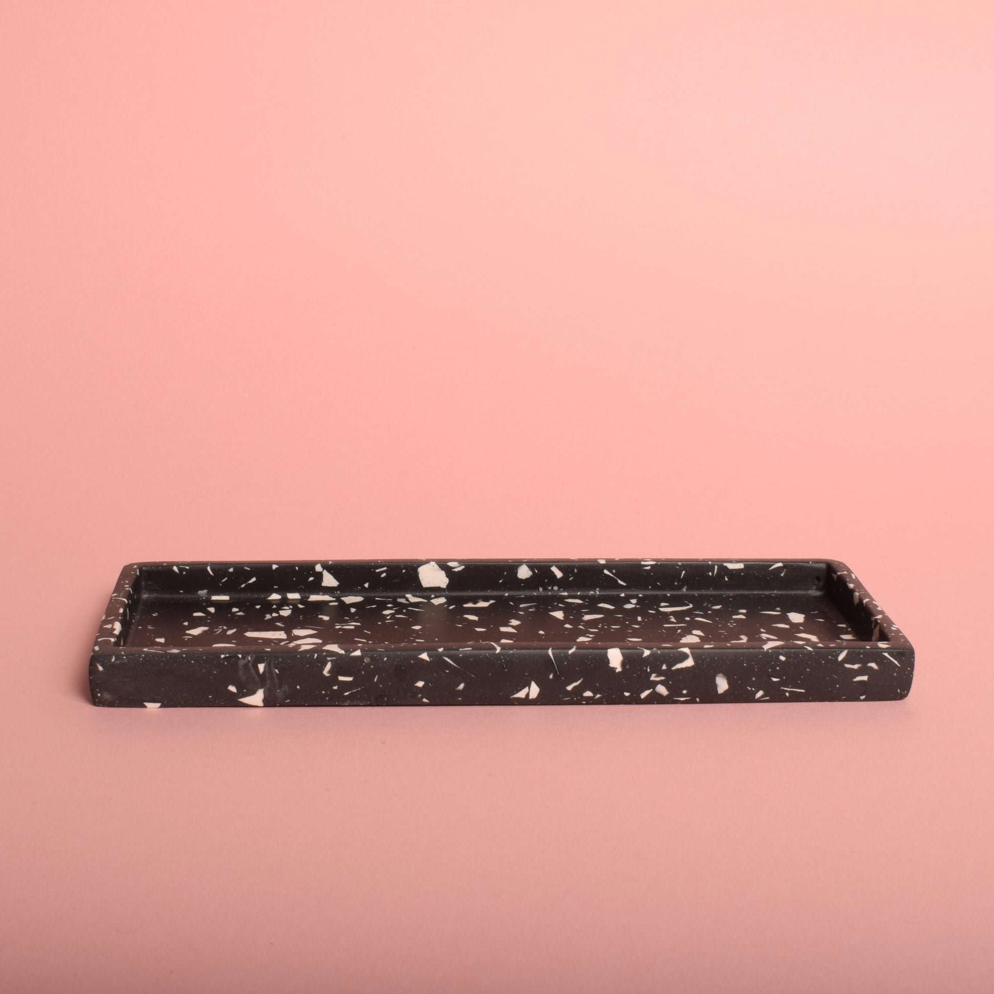 A black rectangular trinket tray with white terrazzo chips