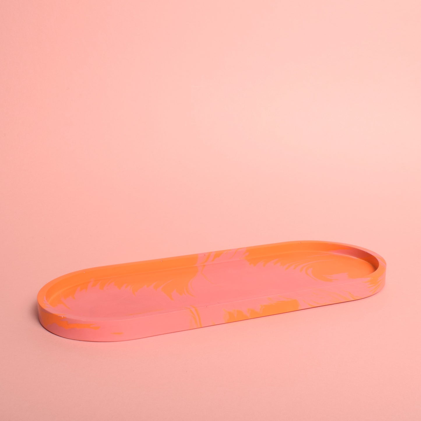 A large oval pink and orange marble effect trinket tray.