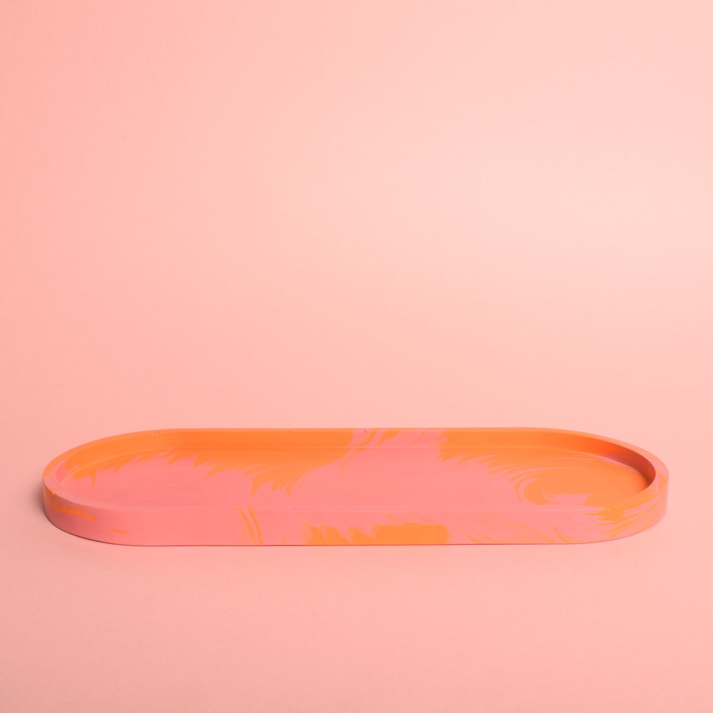 A large oval pink and orange marble effect trinket tray.