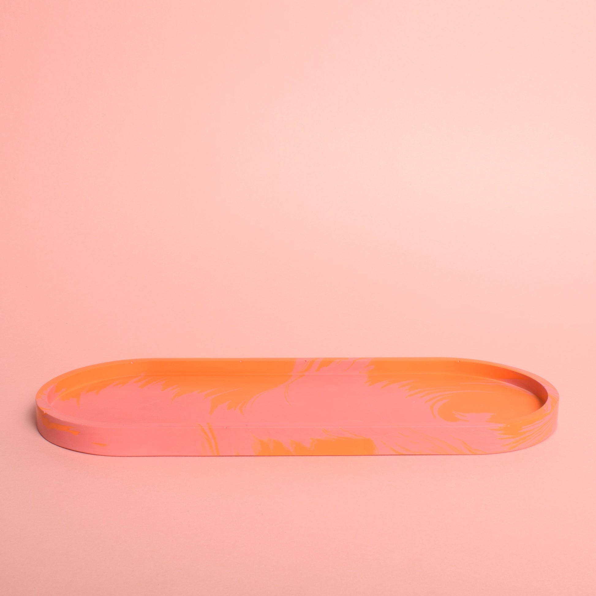 A large oval pink and orange marble effect trinket tray.